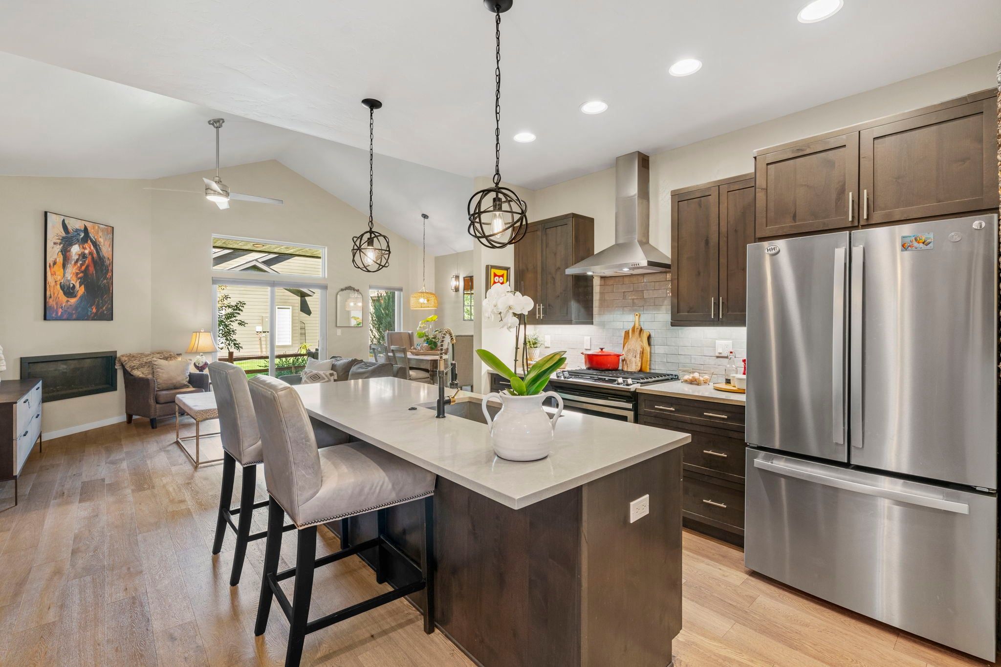 A modern kitchen with a large island, stainless steel appliances, and dark wooden cabinets.