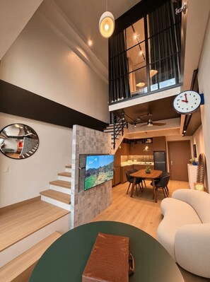 Ein modernes Interieur mit Treppe, Essbereich und Wohnzimmer, inklusive Wand-Fernseher.