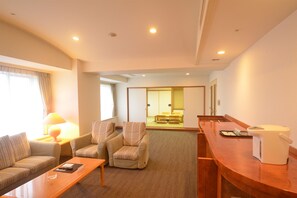 Une chambre d’hôtel comprenant un canapé, des fauteuils, une table à manger et un coin cuisine.