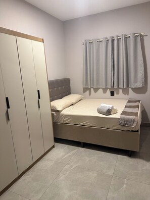 Une chambre à coucher avec un lit, une armoire et un rideau.