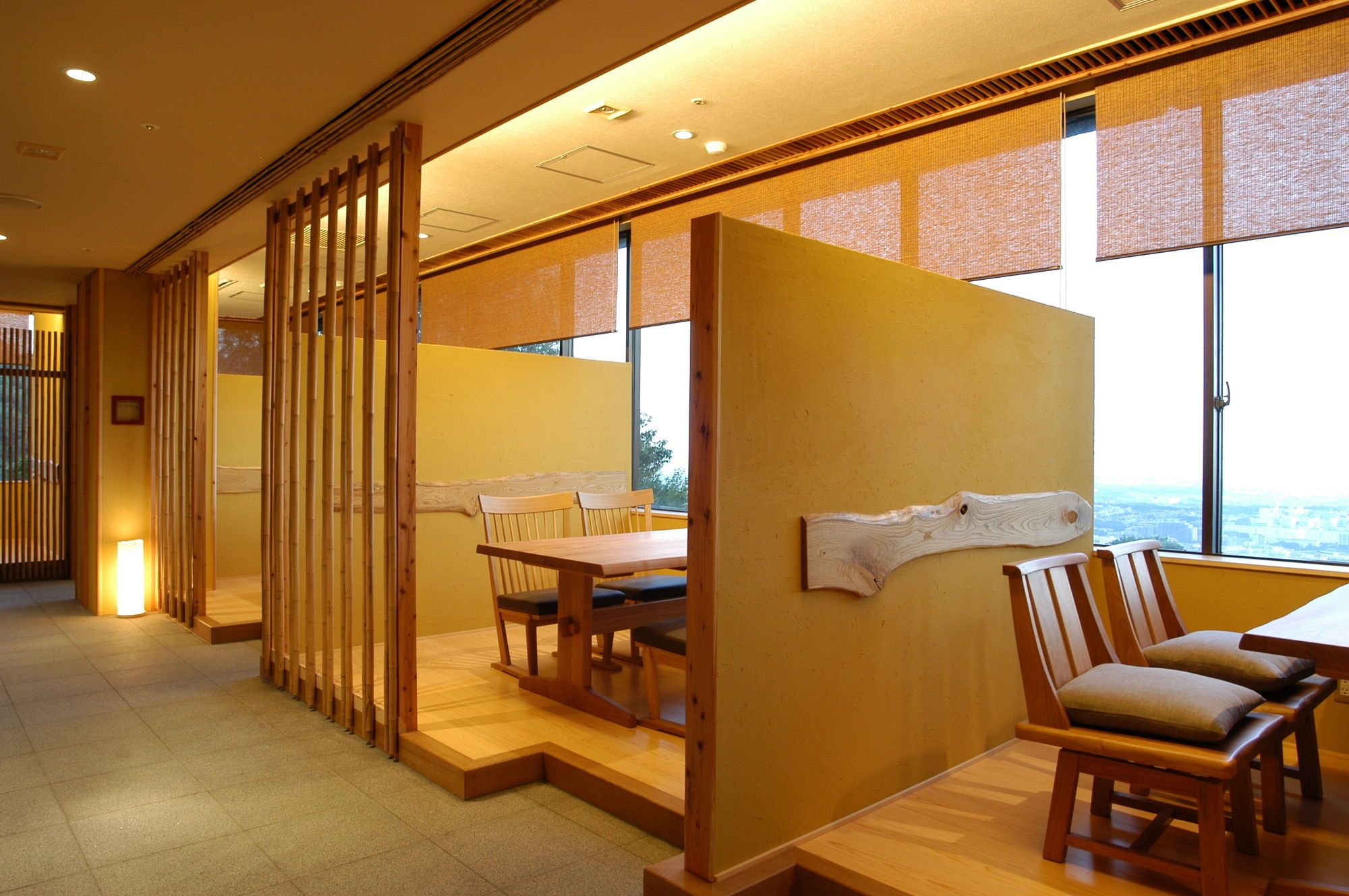A room with a wooden partition, a dining table with chairs, and a view through large windows.