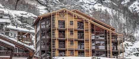 A multi-story building with a wooden facade, labeled '22 SUMMITS,' set against a snowy mountainous backdrop.