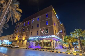 A multi-story hotel with a ground-level entrance, palm trees, and a parking area. - Al Muhaidb Residence Al Malaz 1 (Riyadh)