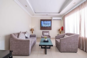 A modern living room with two sofas, a coffee table, and a flat-screen TV mounted on the wall. - Al Muhaidb Khanshalila (Riyadh)