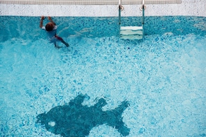 A swimming pool with a tiled edge and a person swimming. - Gemsuites Luxury Serviced Apartments (Nairobi)