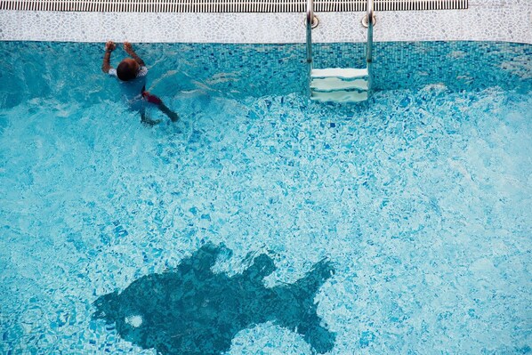 Una piscina amb vora de rajola i una persona nedant.