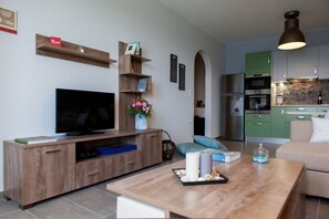 A modern living room with a flat-screen TV, wooden entertainment unit, and a coffee table with candles and decorative items. - Diadema Villa (Naxos)