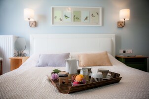 A neatly made bed with a tray of items including a coffee pot, cups, and a box labeled 'SYMPHONIA'.