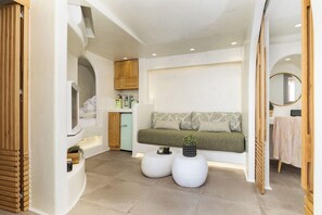 A modern bathroom with a built-in shower, a vanity with a mirror, and a seating area with a bench and cushions. - Korali Boutique Hotel (Naxos)