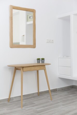 A minimalist room with a wooden console table, two potted plants, a mirror, and a white cabinet. - Korali Boutique Hotel (Naxos)