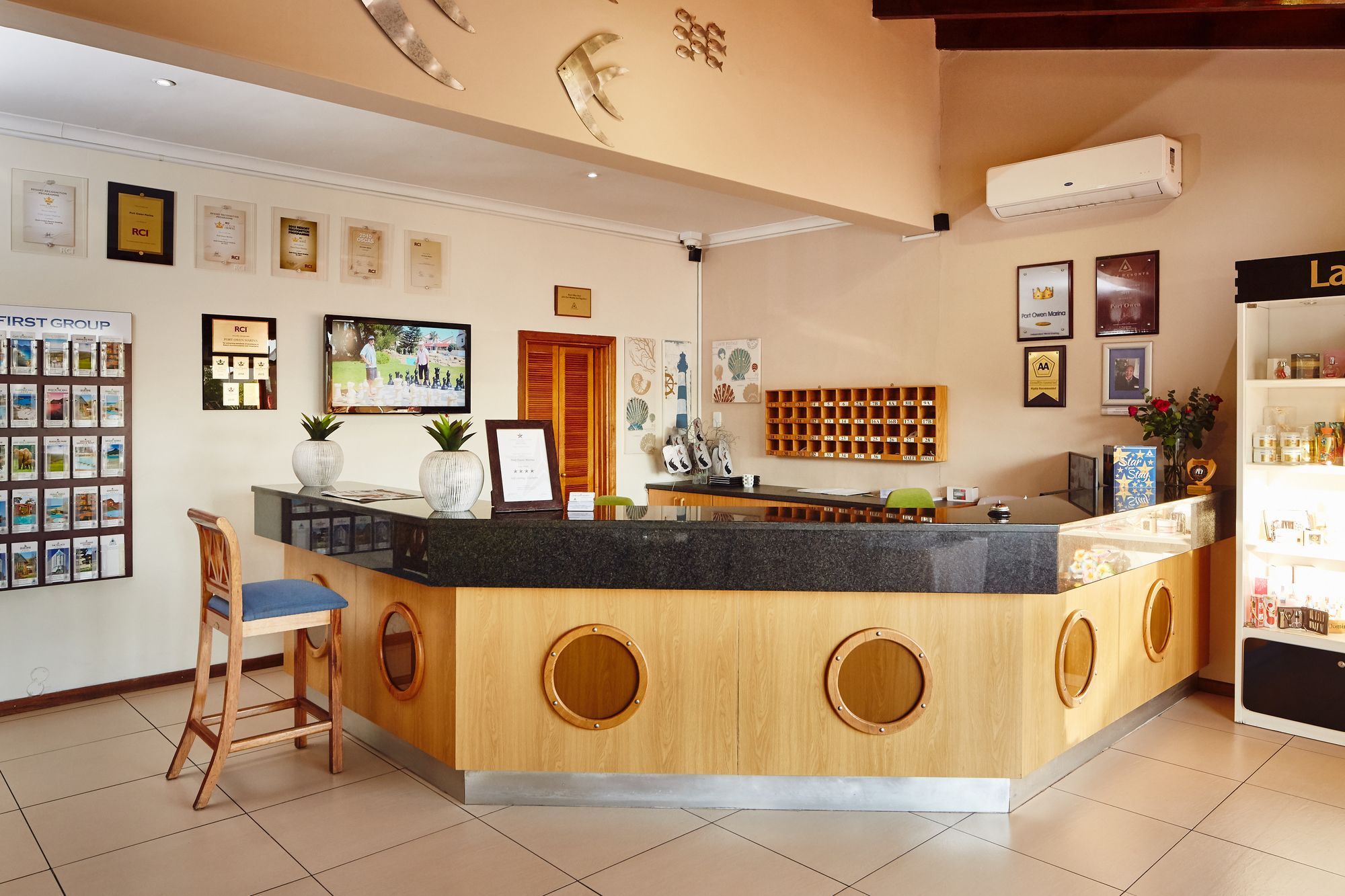 A reception area with a wooden counter, framed certificates, a television, and a wall-mounted air conditioning unit.