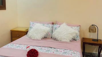 A bedroom with a bed, a nightstand, a lamp, and a patterned rug.
