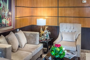 A hotel lobby with a sofa, armchair, decorative lamp, and a painting on the wall. - Almuhaidb Ahamra (Jeddah)
