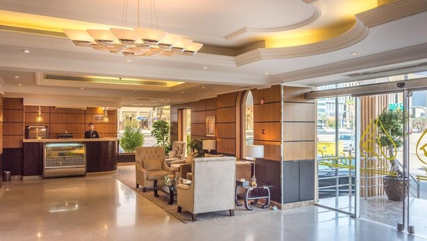 Eine Hotelhalle mit einer Rezeption, einer Sitzecke und großen Fenstern.