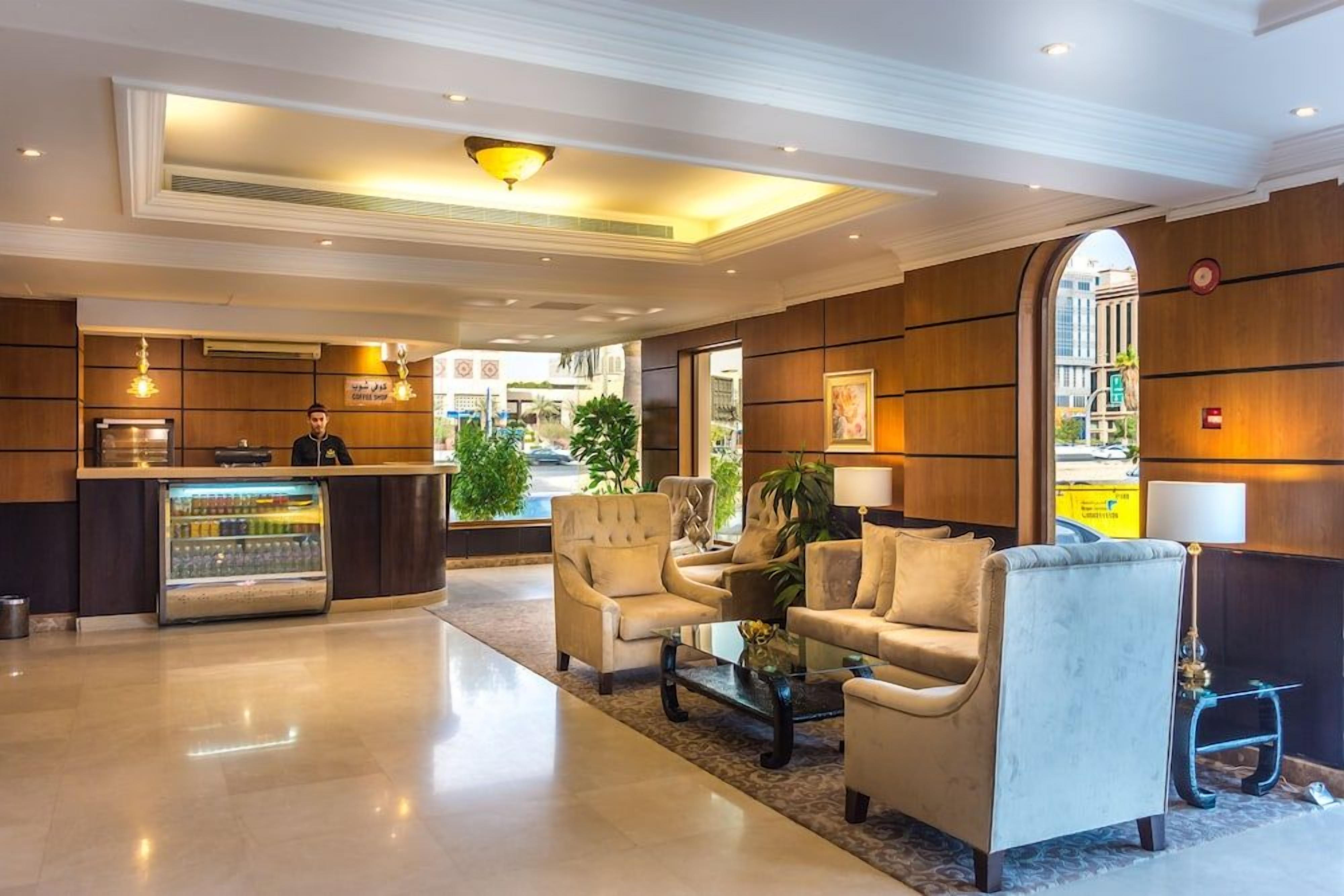 A hotel lobby with a reception desk, seating area, and a view of the street.