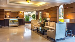 Eine Hotlellobby mit einer Rezeption, einer Sitzecke und Blick auf die Straße.
