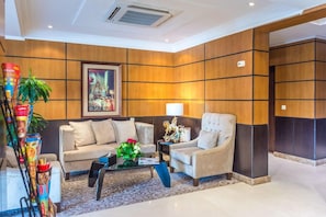 Un vestíbulo moderno con un sofá, sillones, una mesa de centro y una planta decorativa.