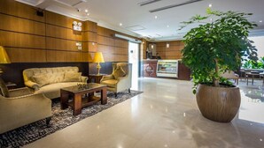 Eine Lobby mit einer Sofagarnitur, einem Couchtisch, einer Zimmerpflanze und einem Empfangsbereich.