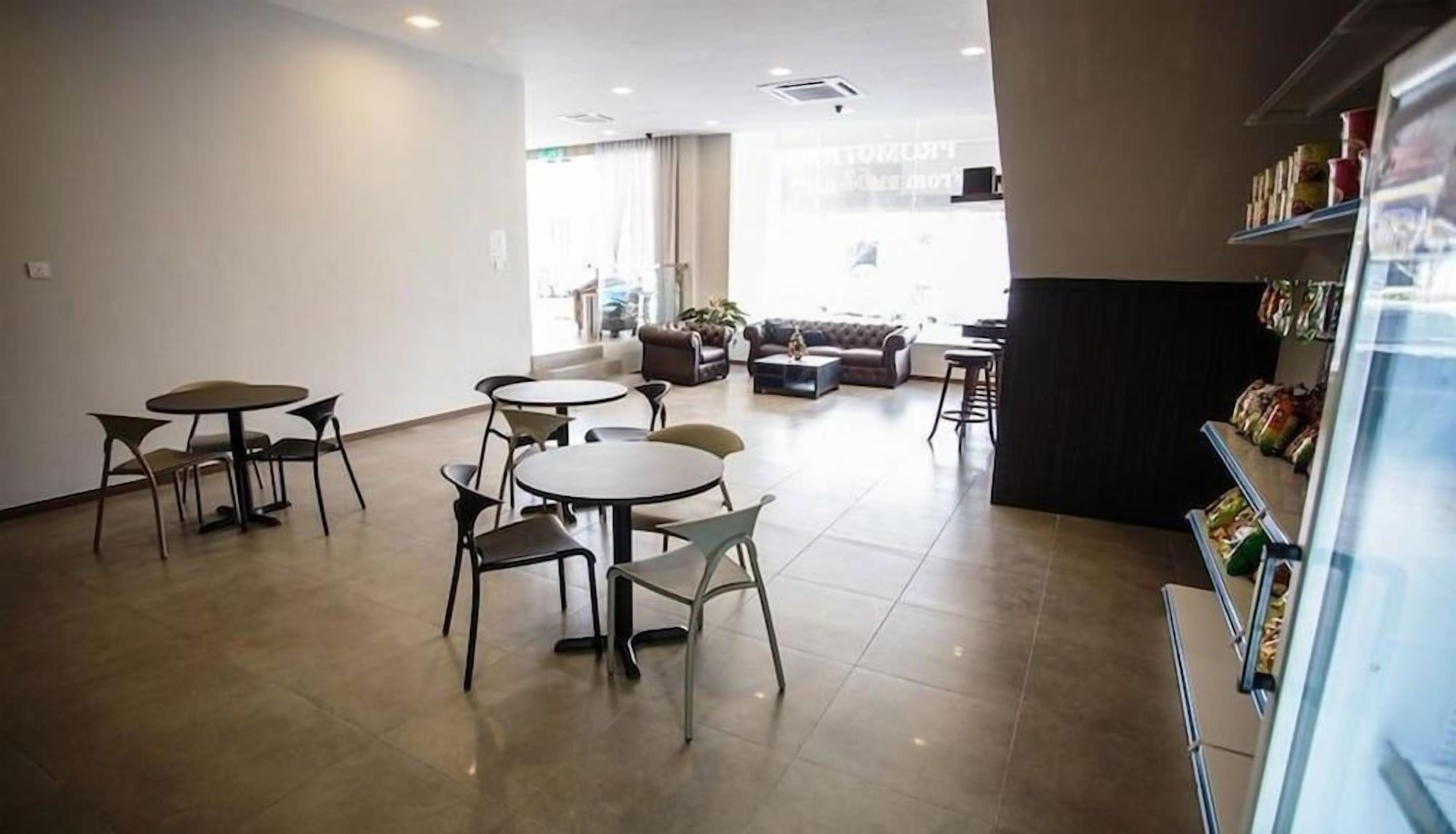 A spacious indoor area with multiple seating arrangements including tables and chairs, a sofa, and a counter with food items.