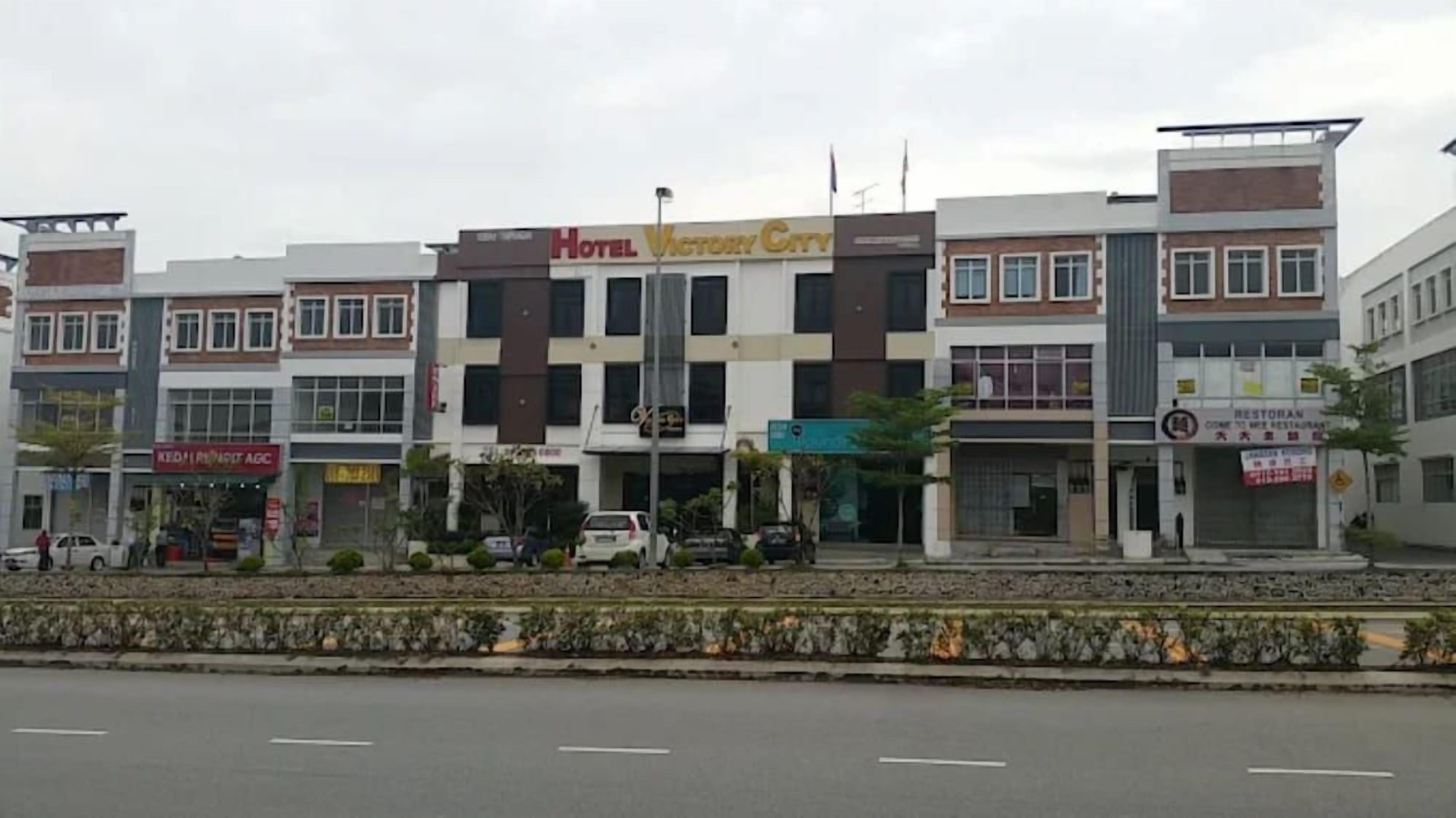 Un hôtel à plusieurs étages, doté d’une entrée principale et entouré de divers commerces et entreprises.