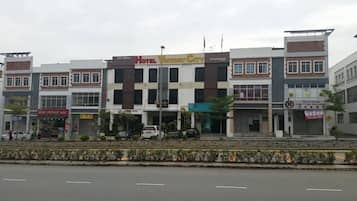 A multi-story hotel with a central entrance, surrounded by various shops and businesses.