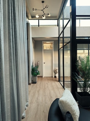 Um interior moderno com ventilador de teto, porta que dá para outro quarto e vista através de janelas amplas.