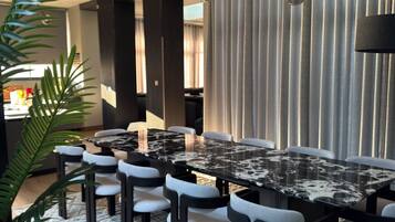 Un espace repas moderne avec une table et des chaises en marbre, un luminaire suspendu et un tapis à motifs.