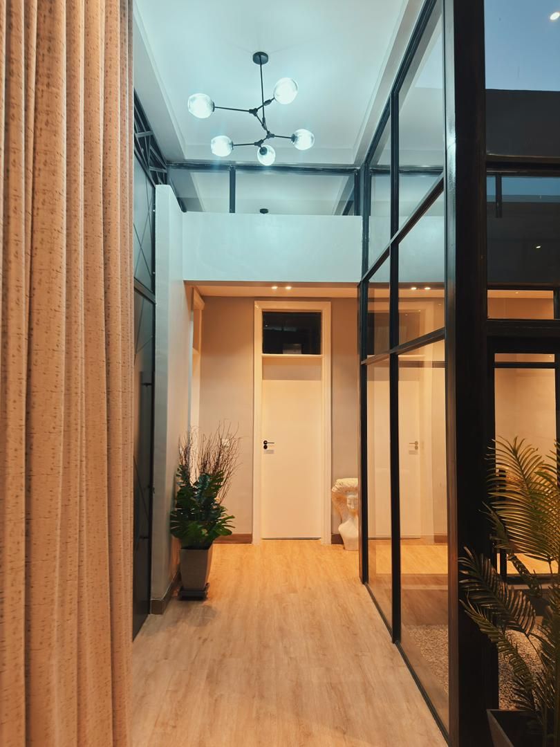 A modern hallway with a wooden floor, a glass door, and a ceiling light fixture.