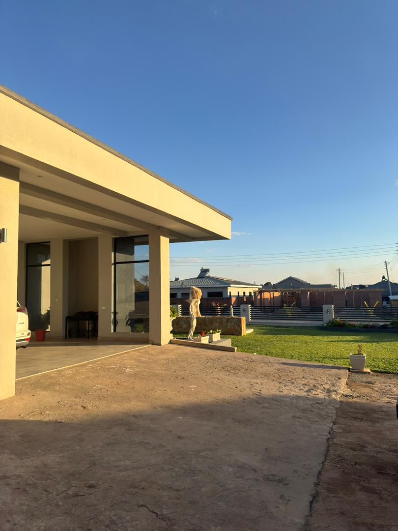 Un bâtiment moderne doté d’un espace extérieur couvert, d’une allée pavée et d’une pelouse.