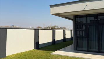Un bâtiment moderne doté d’un toit plat, d’une partie avec des portes vitrées et d’une pelouse bien entretenue.