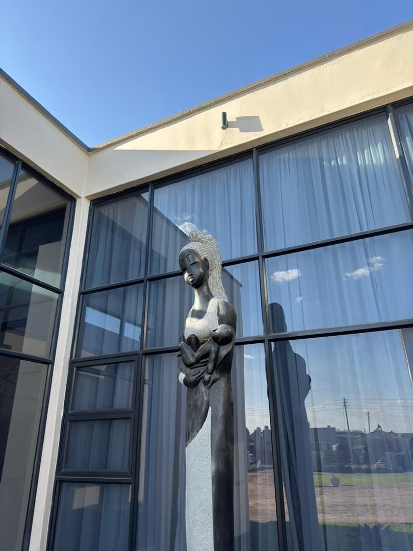 Fachada de edificio con ventanas amplias y una escultura.