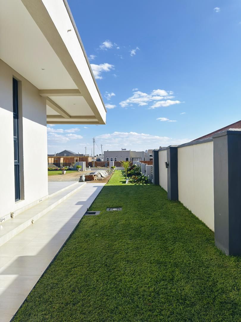 Una zona residencial moderna con un césped cuidado, un sendero y un cielo despejado.