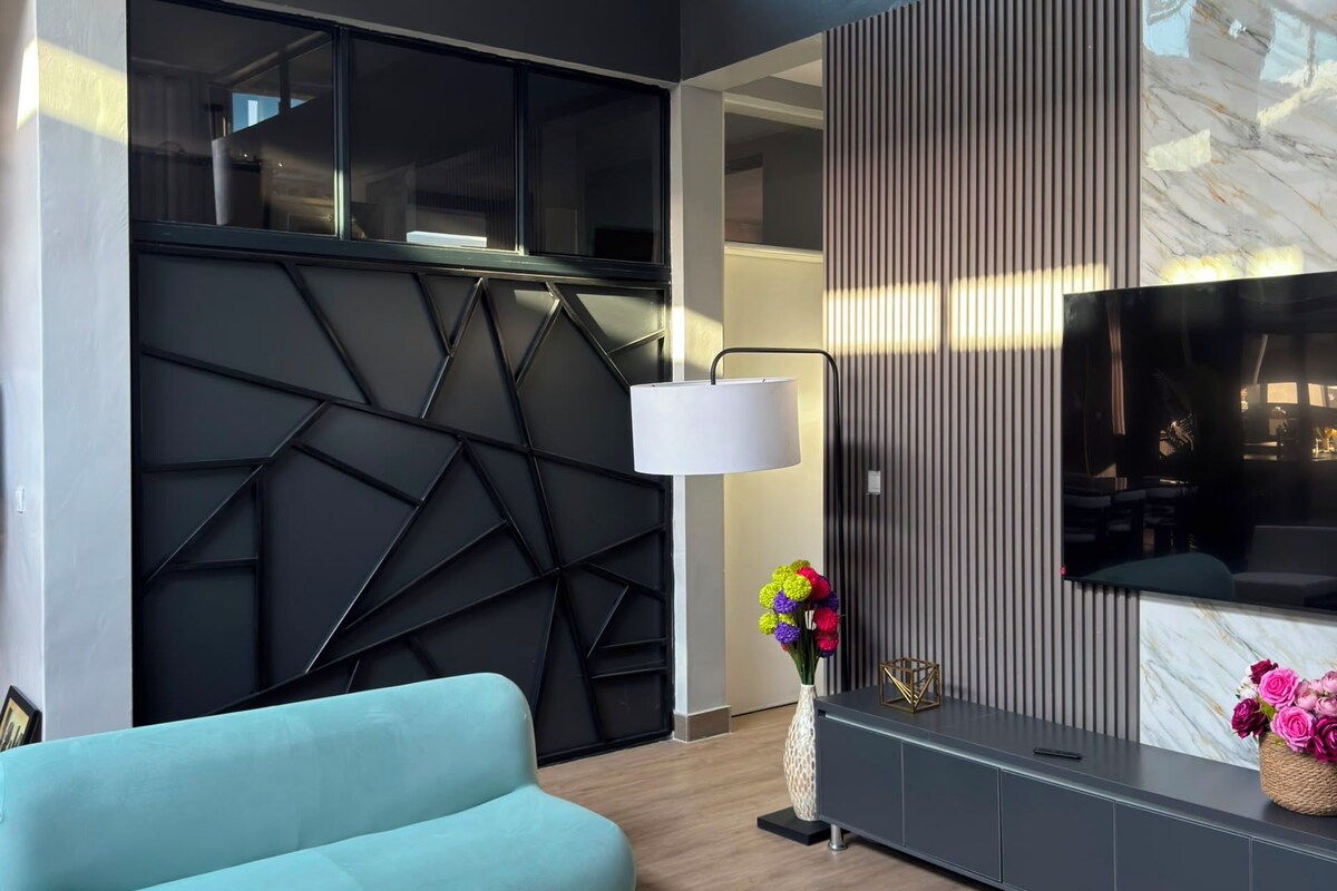 A modern living room with a sofa, a TV, a lamp, and a decorative vase.