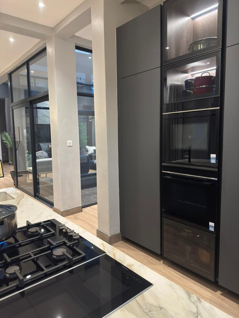 A modern kitchen with a built-in stove, oven, and glass-fronted cabinets.