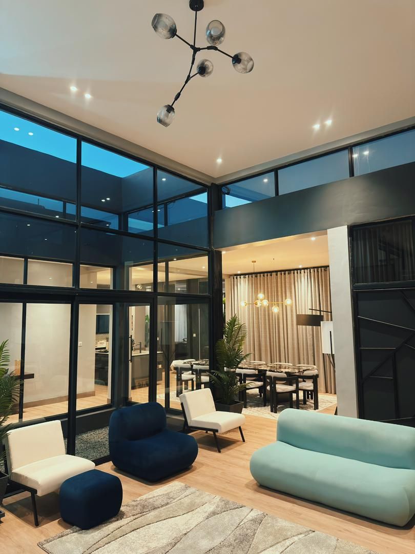 A modern living room with a glass wall, a dining area, and a staircase.