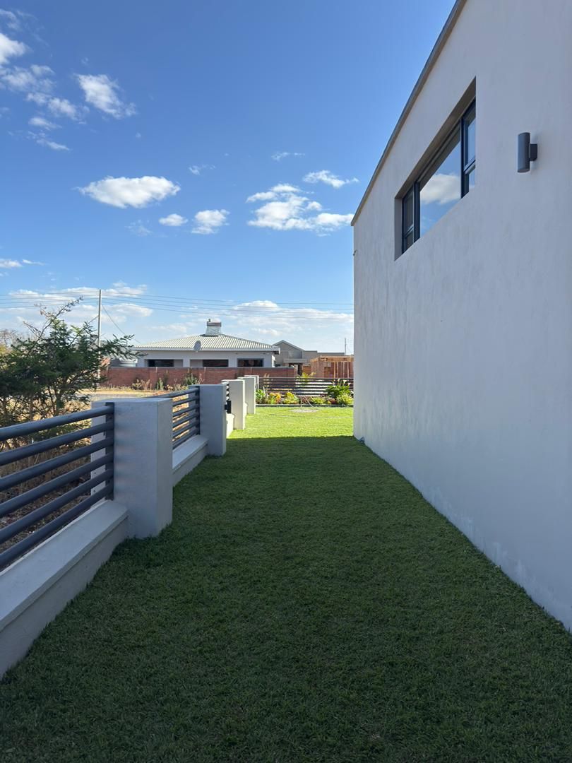 A pathway leading to a building with a white exterior and a window, surrounded by a well-maintained lawn.