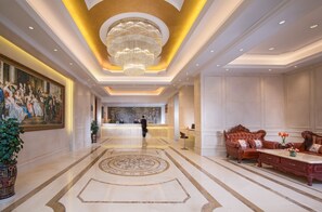 A hotel lobby with a grand chandelier, a reception desk, and a seating area with a sofa and armchairs. - Vienna Hotel Shenzhen (Shenzhen)