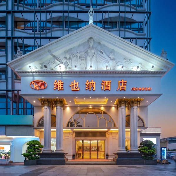 A hotel entrance with a classical facade, columns, and a large illuminated sign. - Vienna Hotel Shenzhen (Shenzhen)