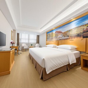 A hotel room with a large bed, a desk, a chair, a television, and a painting on the wall. - Vienna Hotel Shenzhen (Shenzhen)