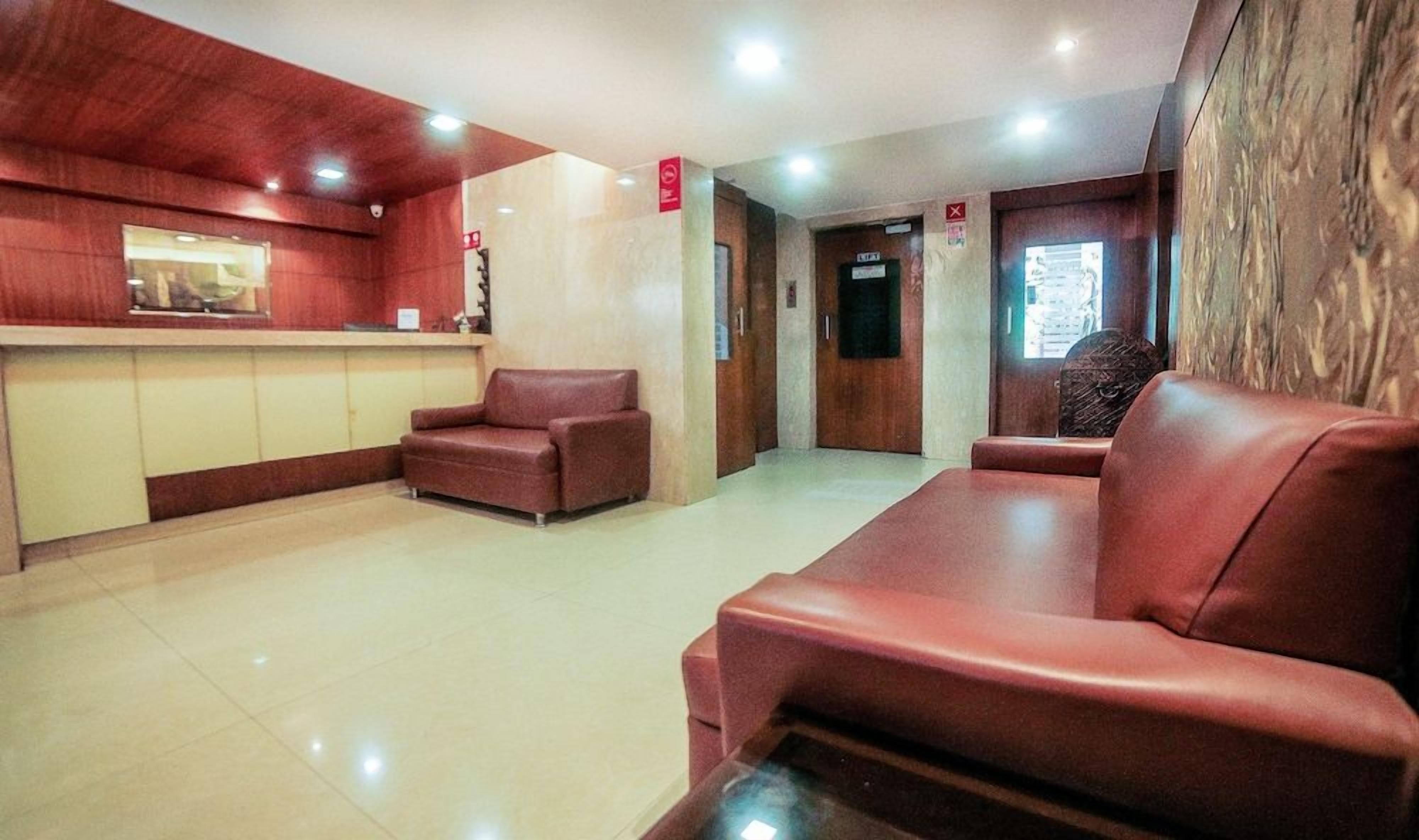 A lobby with a reception desk, two leather sofas, and a wooden wall.