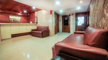 A lobby with a reception desk, two leather sofas, and a wooden wall.