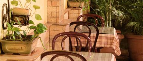 Un patio al aire libre con paredes de ladrillo, plantas en macetas y una mesa lista para comer.