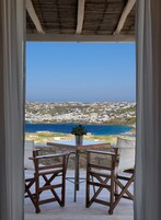 Una terraza con mesa y sillas, con vistas a un pueblo costero y al mar.