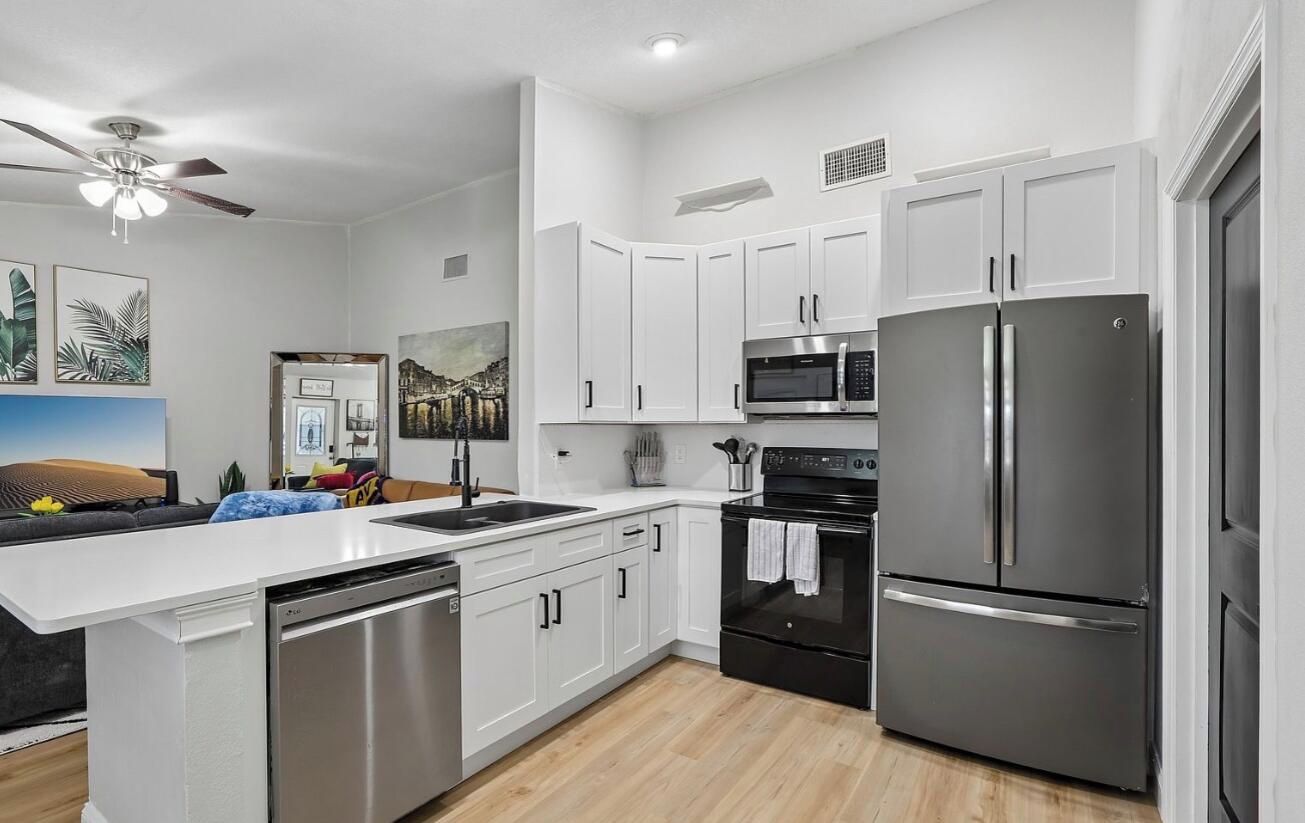 A modern kitchen with white cabinetry, stainless steel appliances, and a central island.