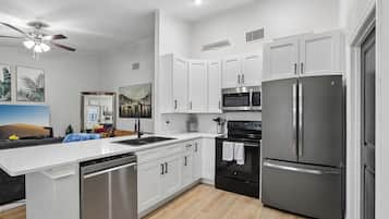 A modern kitchen with white cabinetry, stainless steel appliances, and a central island.