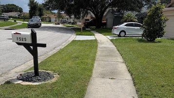 A residential street with a mailbox, a sidewalk, and houses.