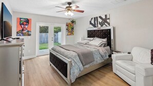 Una camera da letto con un letto, una ventola a soffitto, un divano bianco e opere d'arte alle pareti.