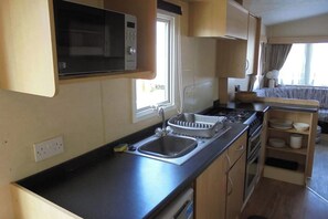 A compact kitchenette with a microwave, sink, and stove. - 3 Bedroom Seaside Cabin Sleeps 6 - Indoor Pool (Skegness)