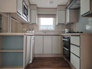 A compact kitchen with a built-in microwave, a sink, and a stove.