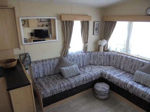 A cozy living area with a sofa, a television, and a window with curtains.